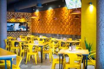 Área de mesas de La Penitencia Restaurante con sillas amarillas
